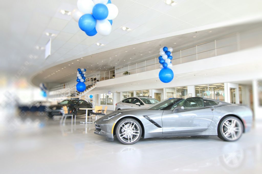 APARISI MOTORS en Algeciras a silver sports car in a showroom with blue and white balloons